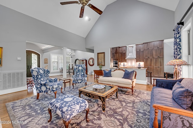 living room featuring arched walkways, high vaulted ceiling, ceiling fan with notable chandelier, visible vents, and light wood finished floors