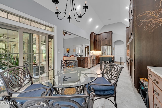 dining room with high vaulted ceiling, arched walkways, and ceiling fan with notable chandelier