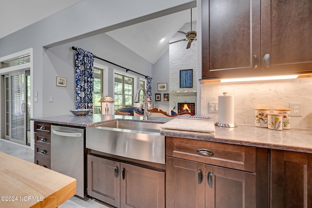 kitchen with dishwasher, lofted ceiling, backsplash, a fireplace, and a sink