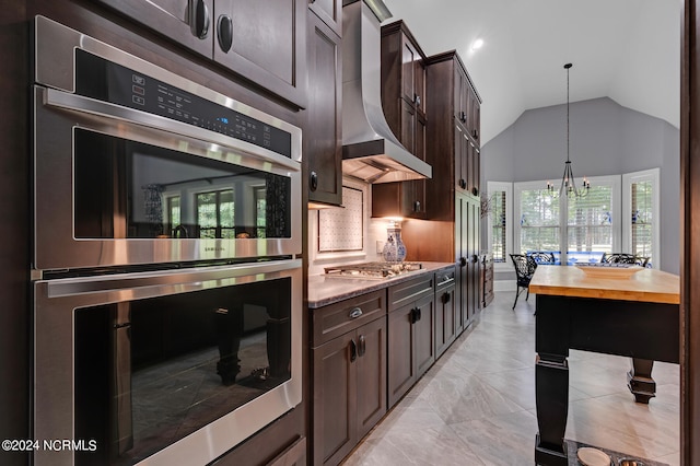 kitchen with appliances with stainless steel finishes, vaulted ceiling, wall chimney range hood, and dark brown cabinets