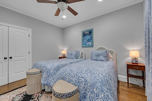 bedroom with wood finished floors, a ceiling fan, baseboards, ornamental molding, and a closet