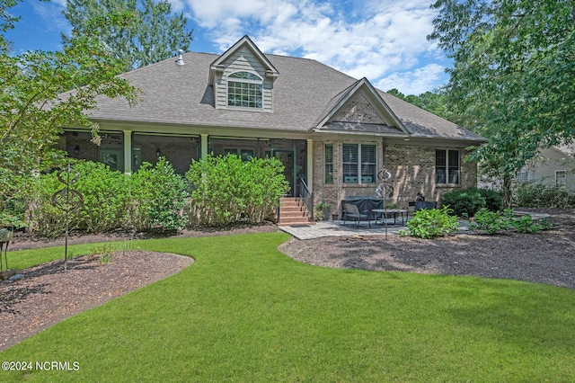 view of front of home with a shingled roof, brick siding, a patio, and a front lawn