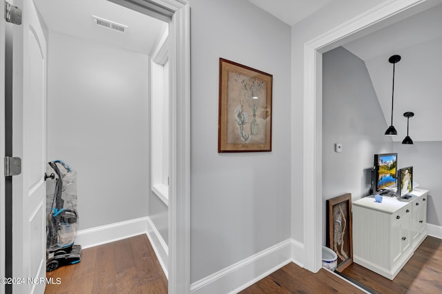 hall with dark wood-style floors, visible vents, and baseboards