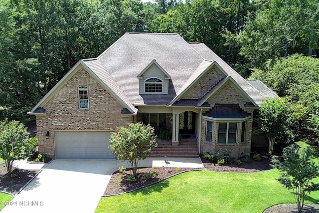 craftsman-style home featuring a front lawn, concrete driveway, brick siding, and an attached garage