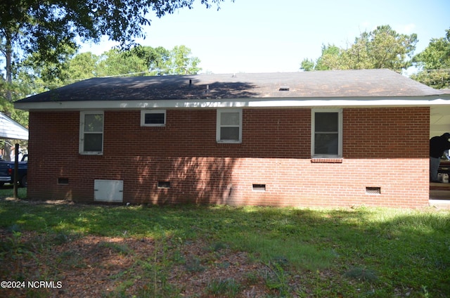 back of house with brick siding, crawl space, and a lawn