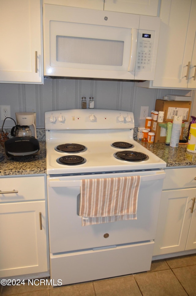 kitchen featuring dark stone countertops, white cabinetry, white appliances, and light tile patterned floors