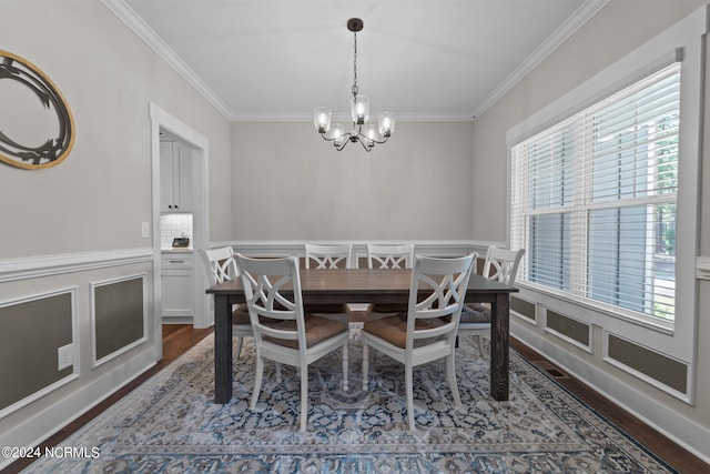 dining area with ornamental molding, hardwood / wood-style floors, and a notable chandelier