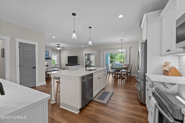 kitchen with dark hardwood / wood-style floors, a center island with sink, stainless steel appliances, white cabinetry, and ceiling fan