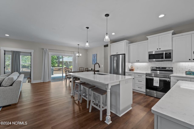 kitchen with white cabinetry, stainless steel appliances, sink, and a center island with sink