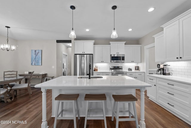 kitchen with light stone counters, stainless steel appliances, white cabinetry, dark wood-type flooring, and tasteful backsplash