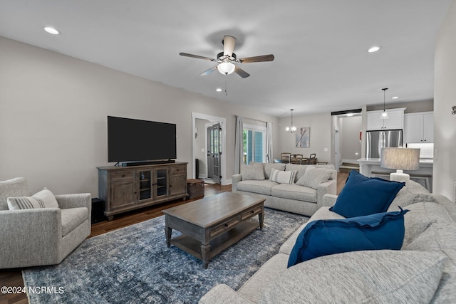 living room featuring ceiling fan with notable chandelier and dark hardwood / wood-style flooring