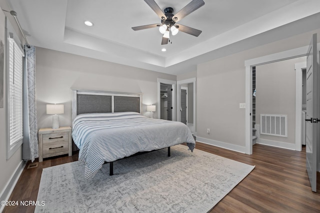 bedroom with a raised ceiling, dark hardwood / wood-style flooring, and ceiling fan