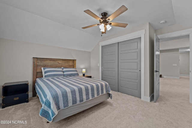 carpeted bedroom with ceiling fan, a closet, and vaulted ceiling