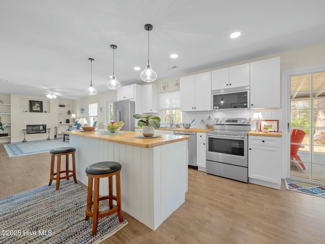 kitchen with light wood-style flooring, appliances with stainless steel finishes, white cabinets, butcher block counters, and ceiling fan