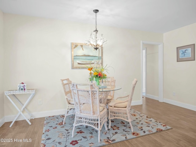 dining area featuring a notable chandelier, wood finished floors, and baseboards