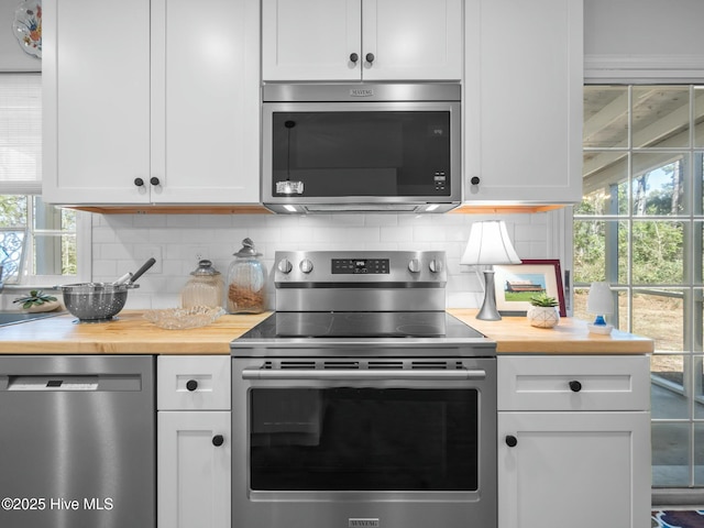 kitchen with butcher block countertops, plenty of natural light, backsplash, white cabinetry, and appliances with stainless steel finishes