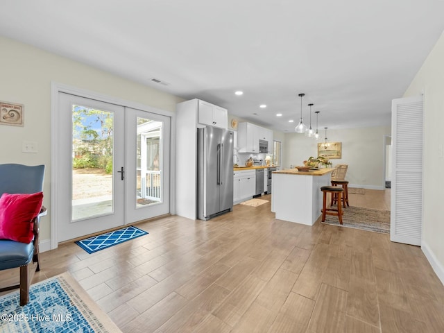 kitchen with visible vents, light wood-style floors, french doors, appliances with stainless steel finishes, and white cabinetry