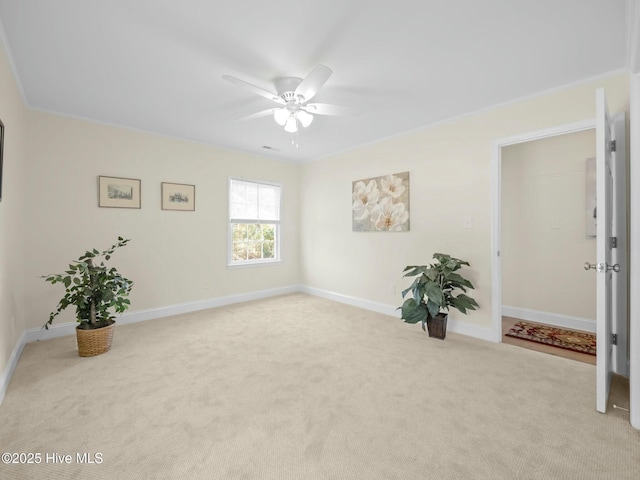 empty room featuring crown molding, carpet, baseboards, and ceiling fan