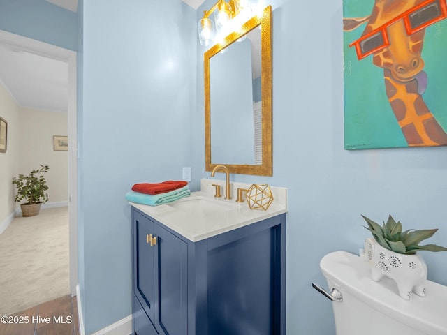 half bath with toilet, vanity, and baseboards