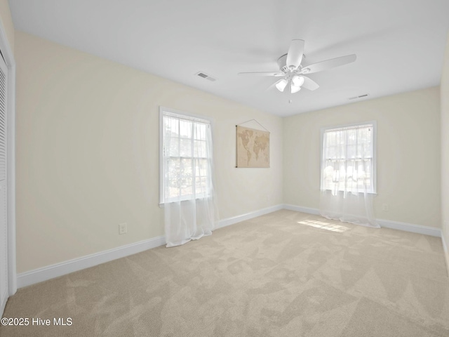 carpeted spare room with baseboards, visible vents, and ceiling fan