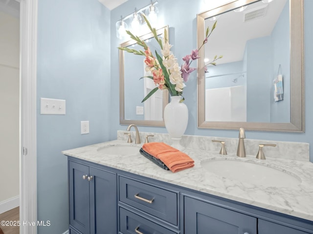 bathroom featuring double vanity, baseboards, visible vents, and a sink