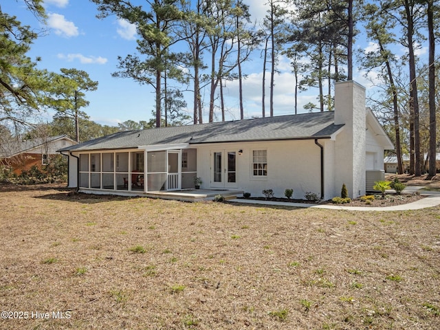 rear view of property featuring a sunroom, french doors, a chimney, a yard, and a garage