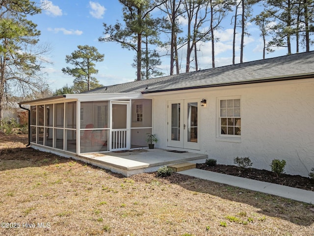 rear view of property with a lawn, a sunroom, and stucco siding