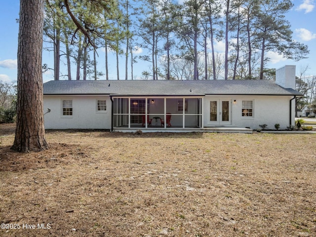 rear view of property featuring stucco siding, french doors, a chimney, and a sunroom