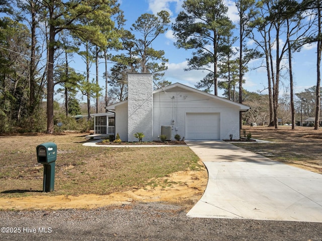 mid-century home featuring central AC unit, a garage, driveway, and a chimney