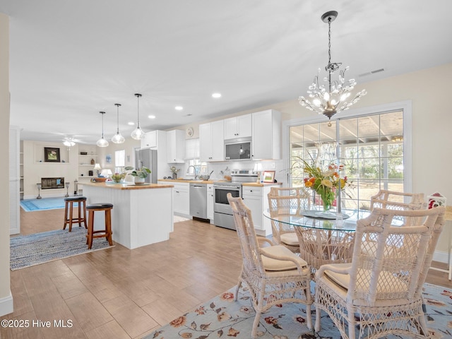 dining area with recessed lighting, visible vents, ceiling fan with notable chandelier, and light wood-style flooring