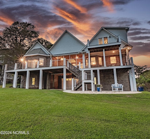 back house at dusk featuring a lawn