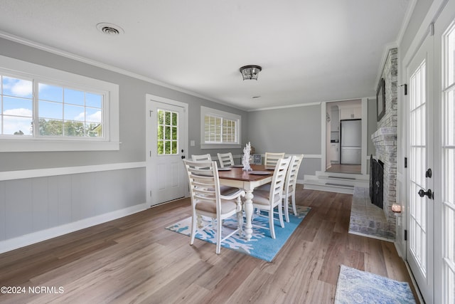 dining space with a fireplace, hardwood / wood-style floors, and ornamental molding