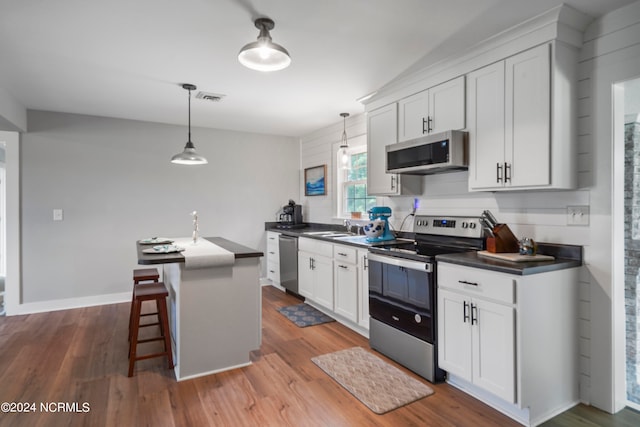 kitchen featuring stainless steel appliances, pendant lighting, light hardwood / wood-style floors, and white cabinets