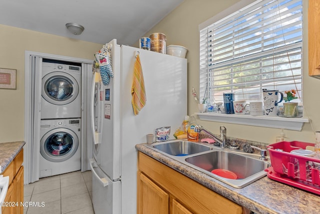 laundry room with laundry area, light tile patterned floors, a sink, and stacked washer and clothes dryer