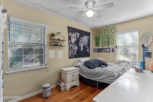 bedroom with baseboards, visible vents, ceiling fan, and wood finished floors