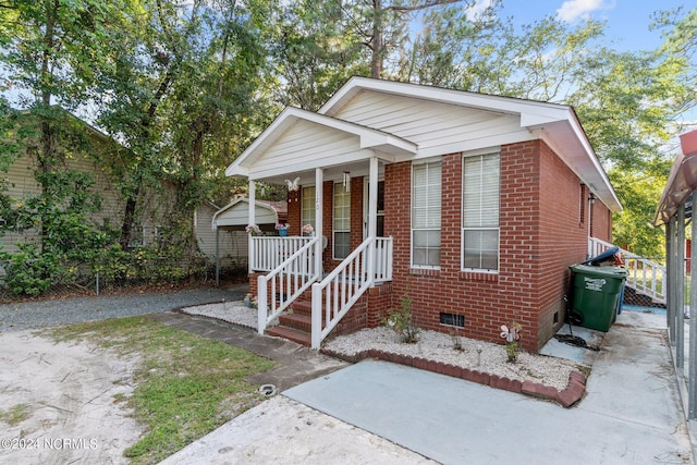 view of front of home with driveway, covered porch, crawl space, and brick siding