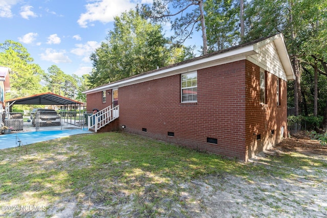 view of home's exterior featuring brick siding, fence, a yard, driveway, and crawl space