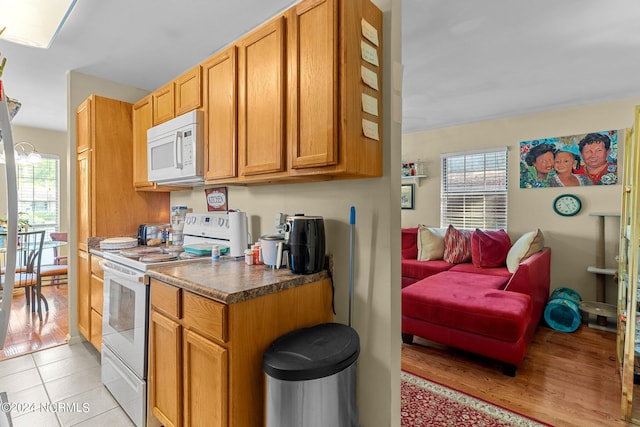 kitchen featuring dark countertops, white appliances, plenty of natural light, and light tile patterned floors