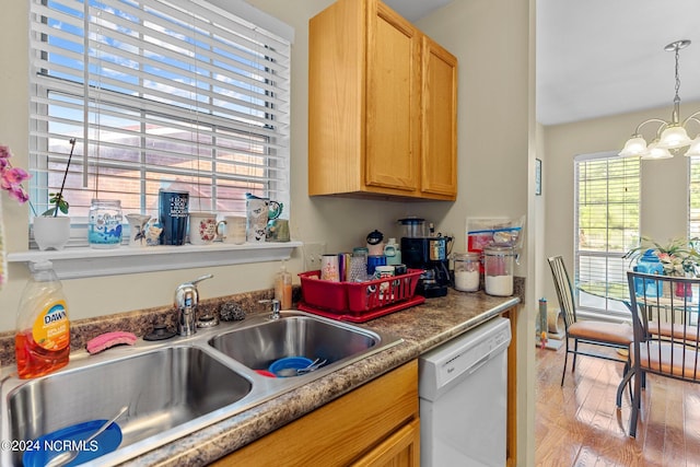 kitchen featuring pendant lighting, an inviting chandelier, light wood-style floors, a sink, and dishwasher