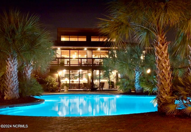 pool at night featuring a patio area