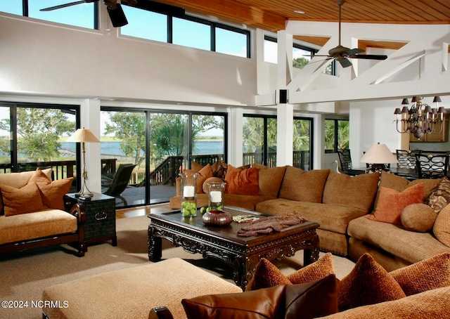 living room featuring ceiling fan with notable chandelier, a towering ceiling, and a healthy amount of sunlight