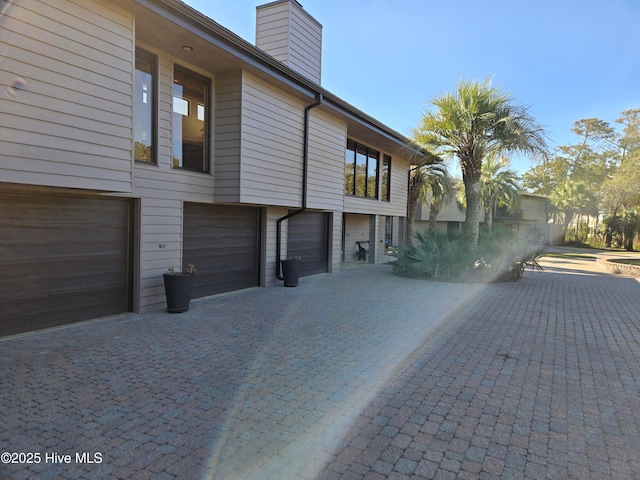 7422 Sea Lilly Ln, Wilmington, NC 28409 - view of side of home with decorative driveway, a chimney, and a garage