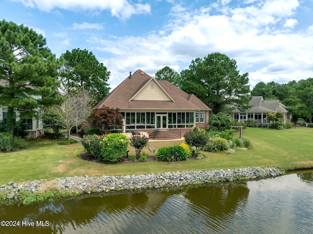 back of property featuring a water view, a yard, a patio, and brick siding