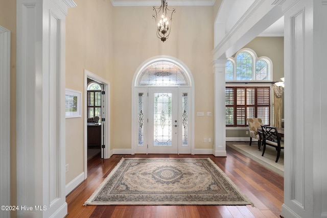 entrance foyer with a chandelier, a high ceiling, dark hardwood / wood-style flooring, and crown molding