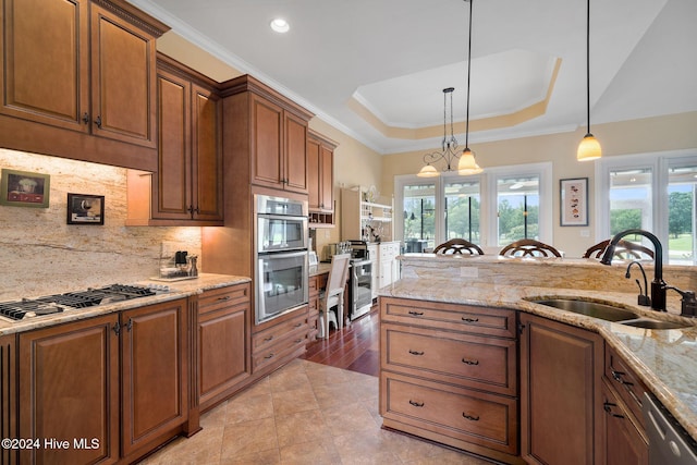 kitchen featuring an inviting chandelier, sink, a tray ceiling, decorative light fixtures, and stainless steel appliances