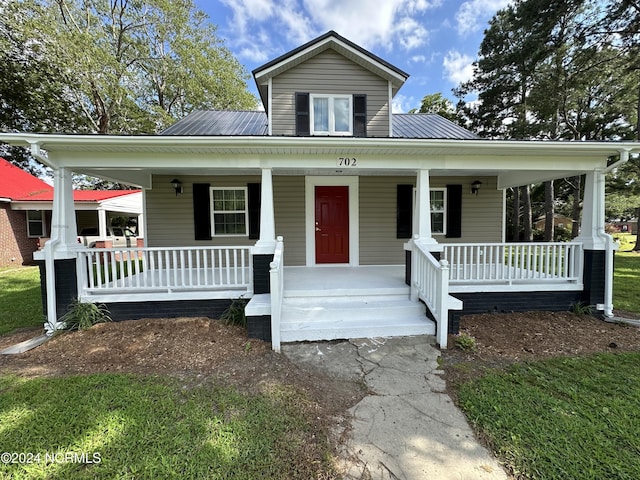 bungalow-style home featuring covered porch and metal roof