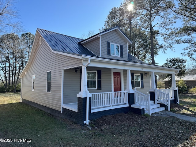 bungalow featuring covered porch, metal roof, and a front yard