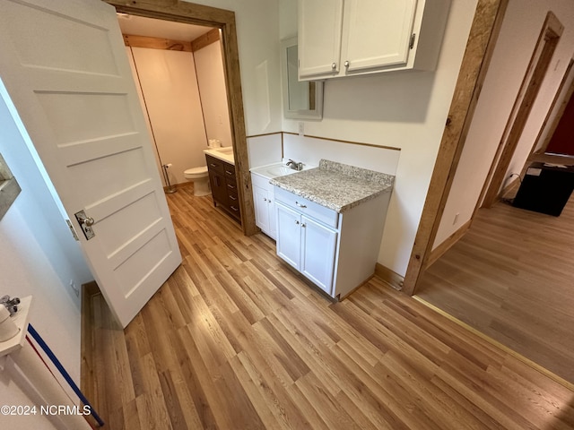 kitchen with white cabinetry, sink, and light hardwood / wood-style floors