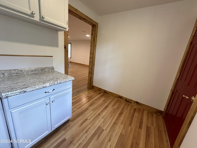 kitchen featuring light stone counters, white cabinets, and light hardwood / wood-style floors