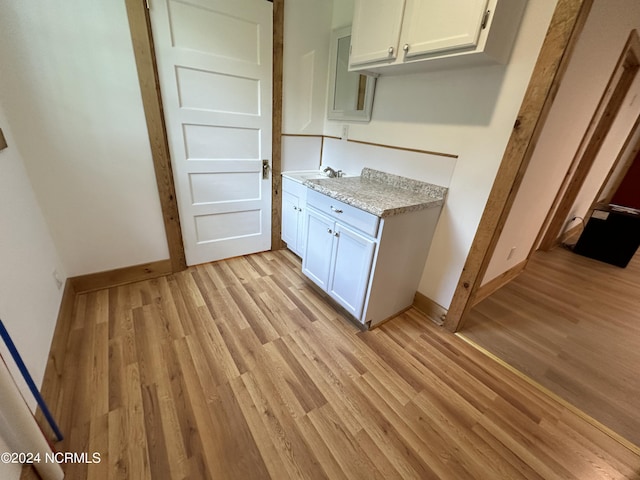 kitchen with white cabinets, light hardwood / wood-style flooring, and sink